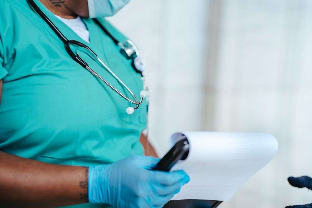 crop black physician with clipboard at work