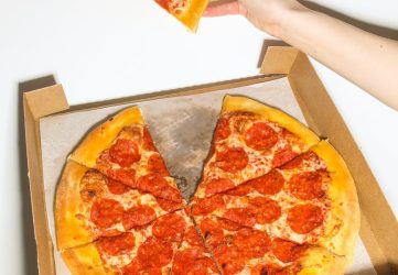 person holding a slice of pizza
