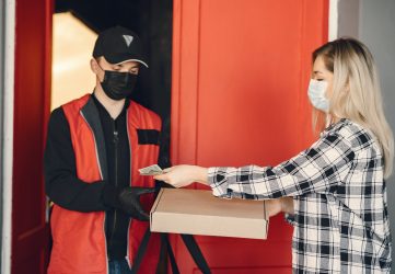delivery person delivers pizza to customer