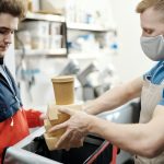 fast food worker puts order in bag for delivery