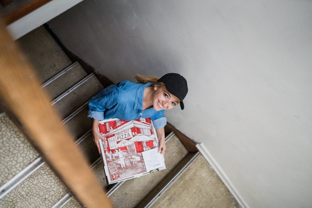 delivery driver climbing stairs with pizza